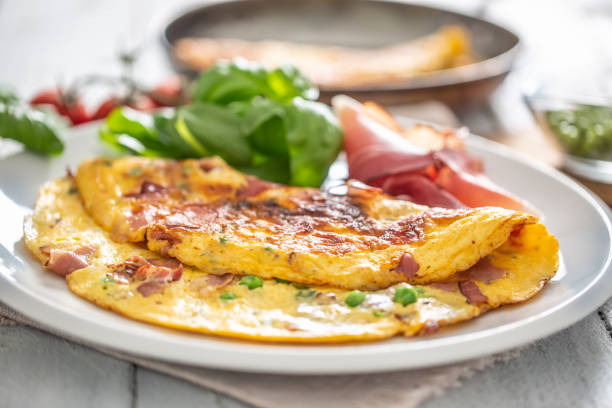 istock Omelette with prosciutto peas basil tomatoes and herbs on white plate 1253617948