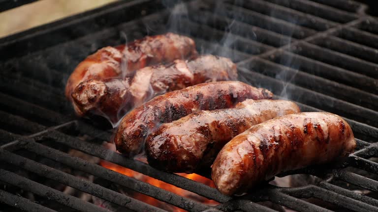 Slow motion close-up sausages being cooked on grill