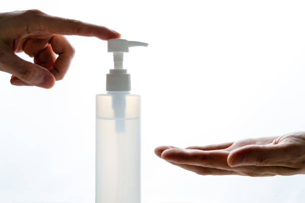 istock Hand silhouette using disinfectant gel bottle with illuminated background 1253624332