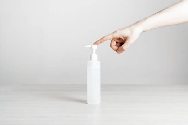 istock Hand squeezing disinfectant gel spray on a table with a white background 1253624333