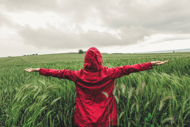 donna che indossa l'impermeabile rosso sotto la pioggia - deep of field foto e immagini stock