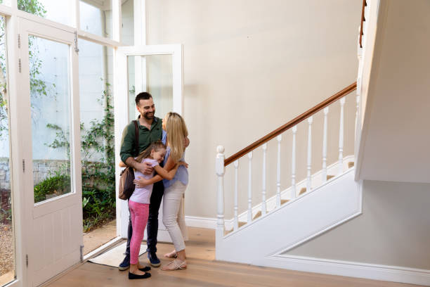 Caucasian couple and their daughter embracing in the hallway Side view of a Caucasian couple and their daughter embracing in the hallway of their house at the front door, the daughter is wearing a backpack looking out front door stock pictures, royalty-free photos & images