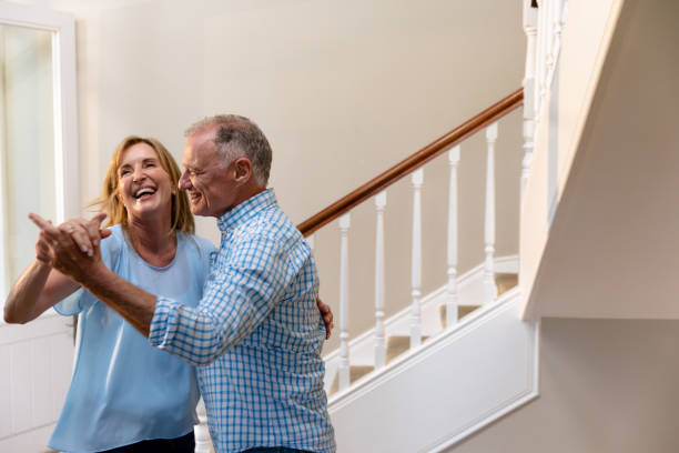 Caucasian couple having fun dancing and smiling in the hallway Side view of a Caucasian couple having fun dancing and smiling in the hallway of their house middle aged couple dancing stock pictures, royalty-free photos & images
