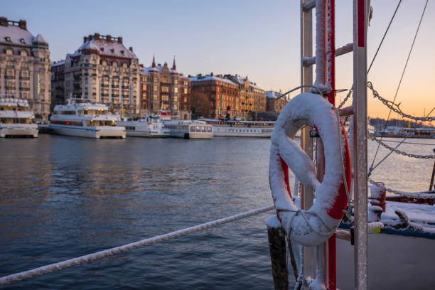 a snow covered life preserver, stored on a water taxi that is docked in a harbor in stockholm, sweden at a winter sunrise. - stockholm harbor sweden winter imagens e fotografias de stock