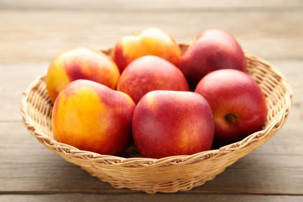 istock Nectarines in a basket on brown background with copy space 1253630227