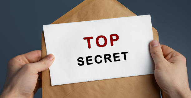 istock Cropped view of man holding craft envelope with text TOP SECRET on blue background 1253633921