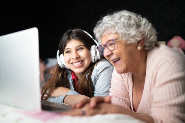 nonna e nipote usano il laptop a casa - grandparent family multi generation family technology foto e immagini stock