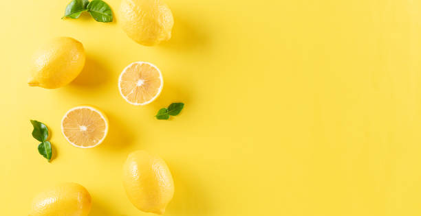 Summer composition made from oranges, lemon and green leaves on pastel yellow background. Fruit minimal concept. Flat lay, top view, copy space.