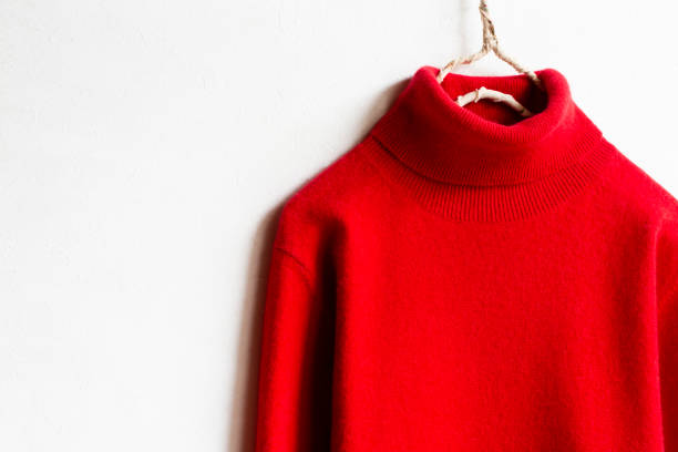 istock red wool sweater hanging on clothes hanger on white background.close up. 1253642722