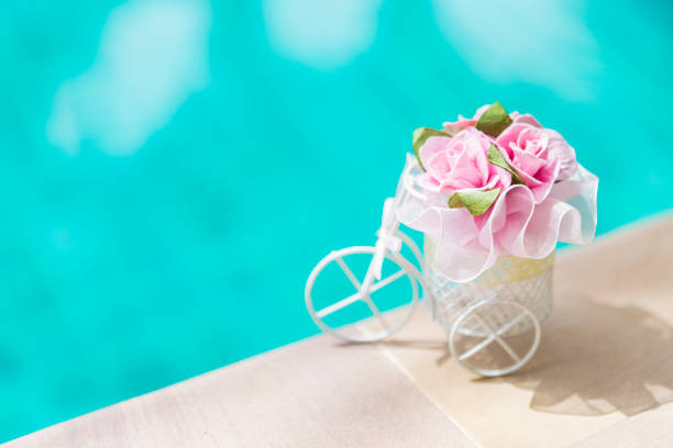 istock Pink paper rose in small bicycle basket over blurred blue water background 1253642918