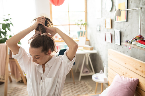 Young woman preparing for a new day in the morning,tying hair bow