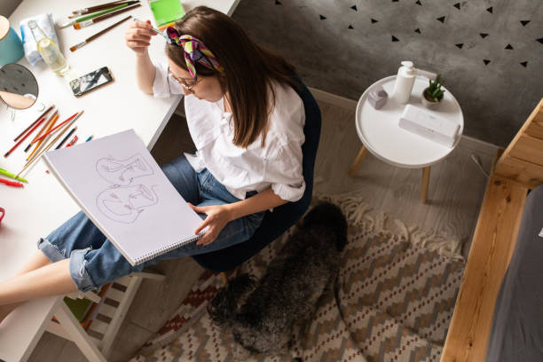 istock Woman sitting at desk and drawing in notepad at home 1253643130