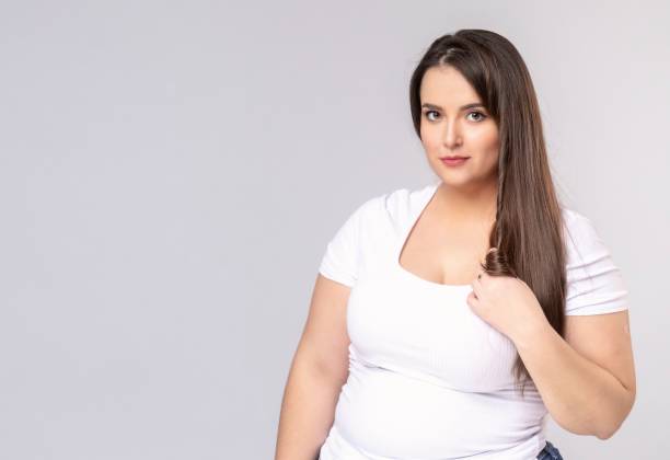 istock Plus Size Model with long hair twists hair on a finger 1253652189