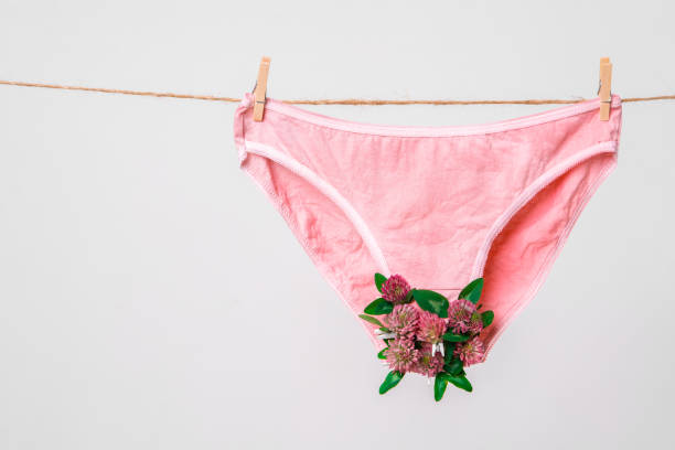 sous-vêtements roses de femmes décorés avec des fleurs sur la corde à linge isolée sur le blanc, la photographie de concept pour le blog féministe - menses photos et images de collection