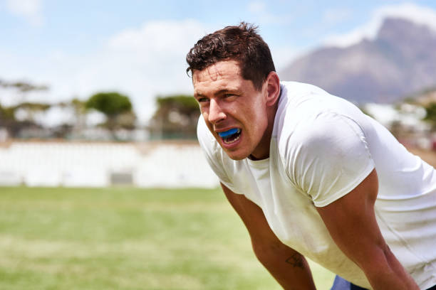 Guard your gums like you guard the ball Shot of a young man wearing a gum guard while playing a game of rugby mouthguard stock pictures, royalty-free photos & images