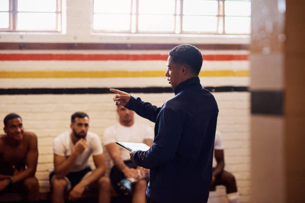 The kind of coaching that can turn a game around Shot of a rugby coach addressing his team players in a locker room Leadership Coaches stock pictures, royalty-free photos & images