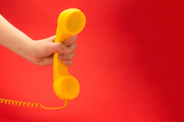 istock Yellow handset on a red background in woman hand. 1253653357