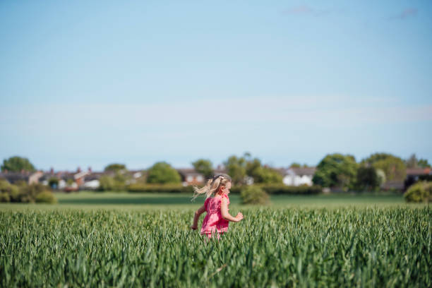 A side view of a young girl running through an agricultural field.
