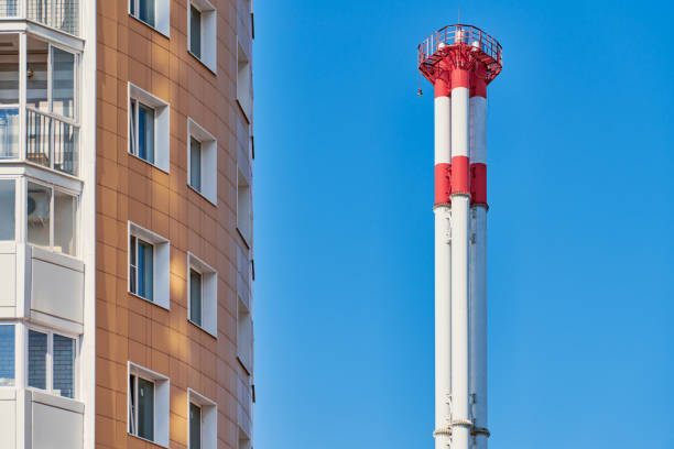 Multistorey building facade and factory chimney. New multi-storey facade, windows and block of flats. Modern apartments complex in high raised building.