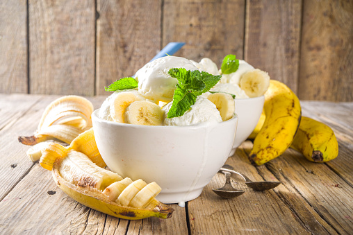 Banana ice cream with min. Vegan fruit ice-cream made of frozen banana in little bowl on wooden background copy space