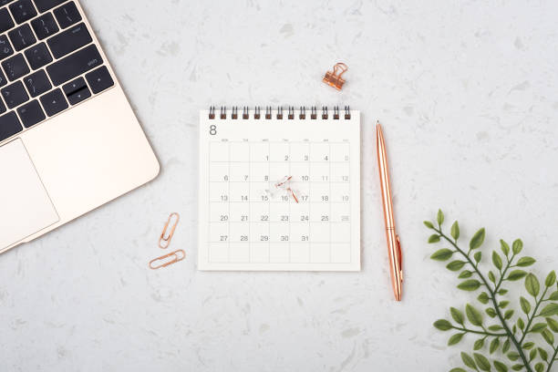 istock Calendar with rose gold pen and laptop on white quartz table 1253661245