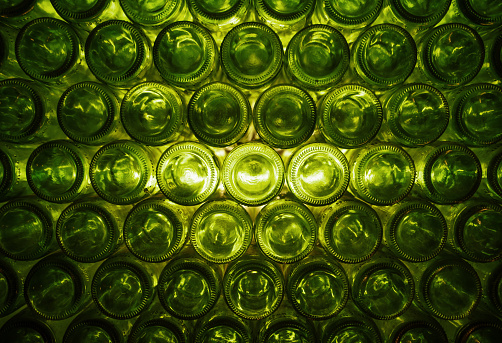 A green pattern / background with back-lit green wine bottles