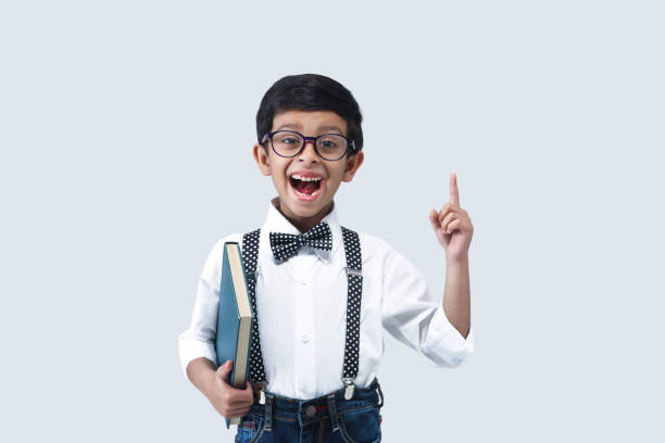 portrait of smiling boy holding book with bag - schoolboy relaxation happiness confidence imagens e fotografias de stock