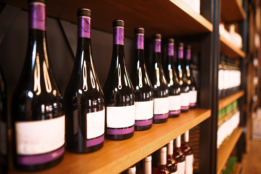 Wine bottles in rows in wooden shelves for sale