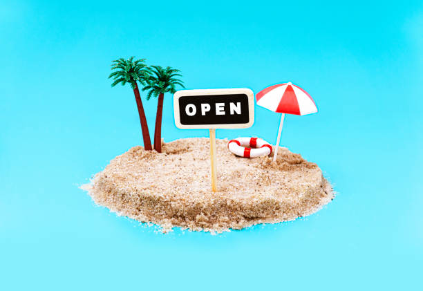 istock Miniature toy island with palm trees and a pole sign saying OPEN on a light blue background. 1253668046