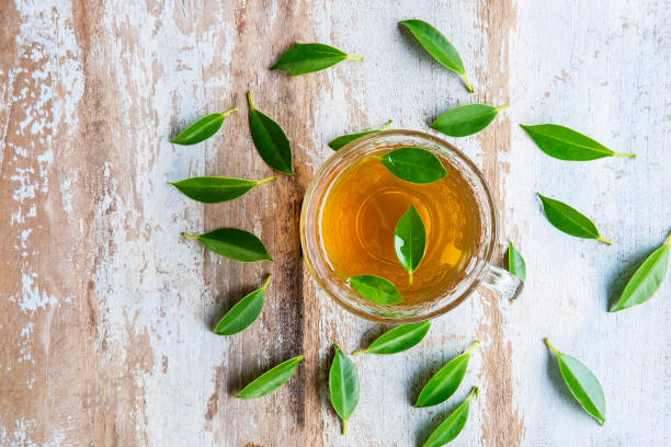 istock Tea cups and fresh tea leaves on a wooden table 1253668214