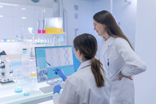 istock Female research team studying DNA samples. Computer screens with DNA helix in foreground 1253668735