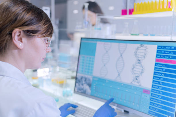 istock Female research team studying DNA samples. Computer screens with DNA helix in foreground 1253668827