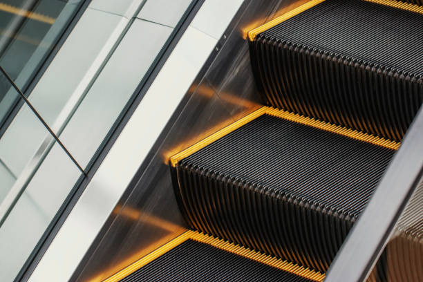 large black escalator with yellow stripes and transparent railing in the shopping center building. - escalator shopping mall shopping transparent imagens e fotografias de stock