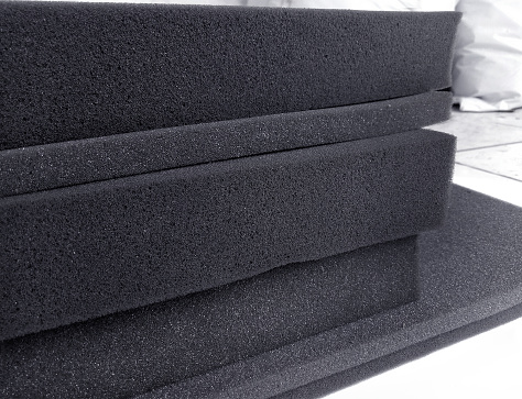 a collection of black sponges that stack with different thicknesses in an industrial room