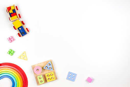 Baby kids toys background. Wooden educational geometric stacking blocks toy, wood rainbow, and colorful blocks on white background. Top view