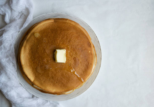 istock A stack of pancakes with a slice of butter on a light background. 1253671739