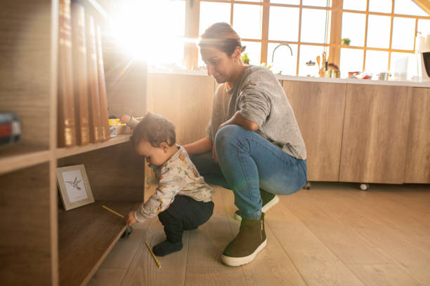 Mother and her little son spending time together at home Side view of mother and her little son spending time together at home baby squatting stock pictures, royalty-free photos & images