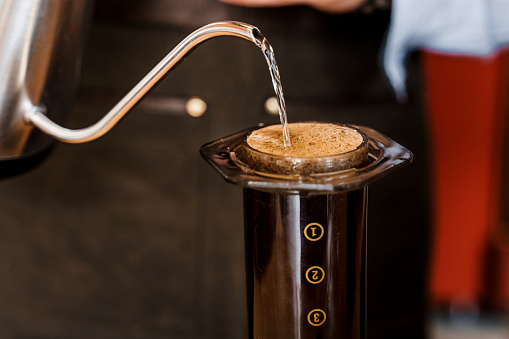 El café Aeropress está cerca de la cafetería. Método de elaboración de café escandinavo. Barista vierte agua para aeroprimir con el café usando kattle. Anuncio para cafetería, restaurantes. photo