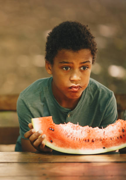 istock A young boy is sitting and eating watermelon 1253672108