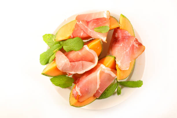 fresh melon slices with prosciutto ham on white background