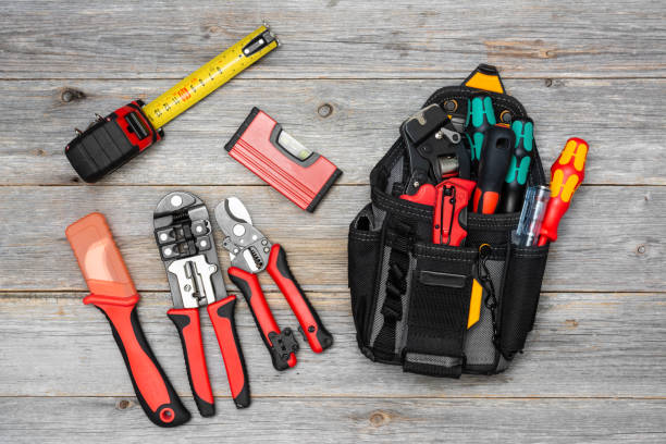 istock Electrician's tools on a gray wooden table. Bag with construction tools for electrical installation. Crimping, screwdrivers, wire cutters, construction tape measure on the table 1253675104