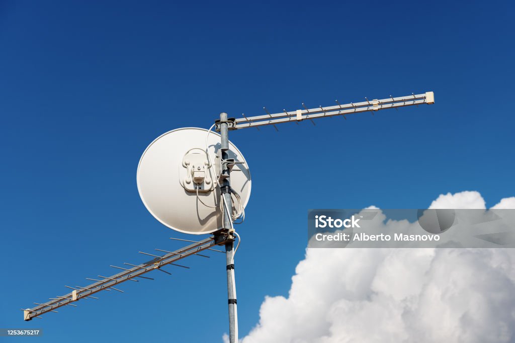 Antena de televisión y antena de satélite en el cielo azul claro con nubes - Foto de stock de Antena de televisión libre de derechos
