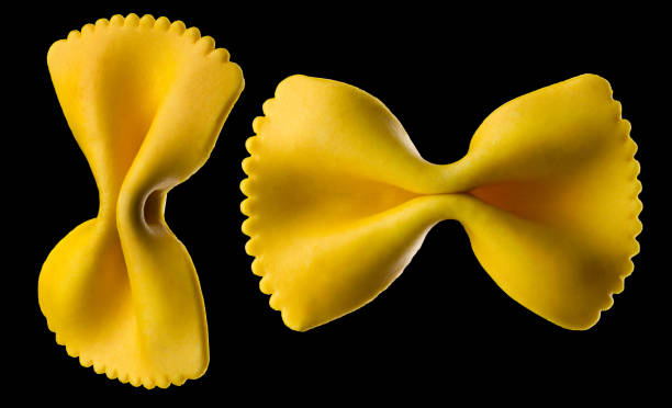 zestaw żółtego makaronu izolowanego na czarnym tle - bow tie pasta italian cuisine bow heap zdjęcia i obrazy z banku zdjęć