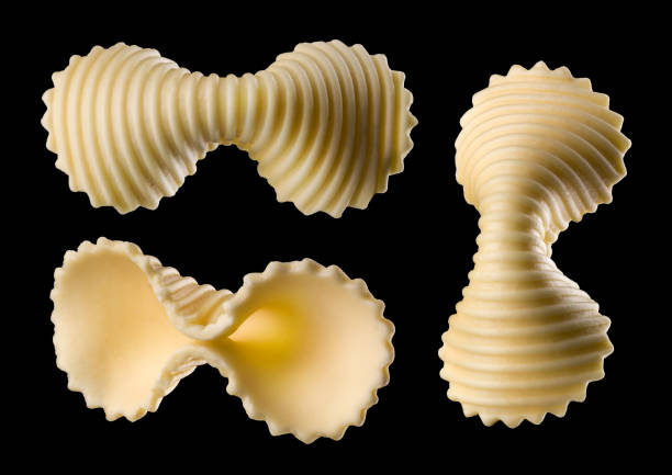 zestaw żółtego makaronu farfalle wyizolowanego na czarnym ze ścieżką przycinającą - bow tie pasta italian cuisine bow heap zdjęcia i obrazy z banku zdjęć