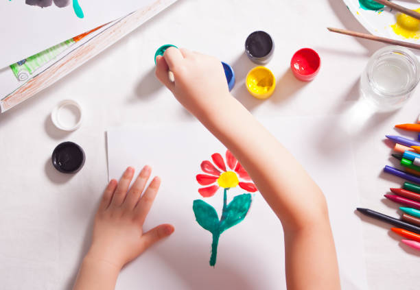 istock A child draws flower with colored paints on the paper. 1253677824