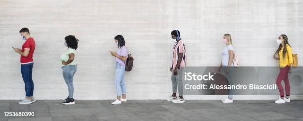 Young People From Different Cultures And Race Waiting In Queue Outside Shop Market While Keeping Social Distance Corona Virus Spread Prevention Concept Stock Photo - Download Image Now