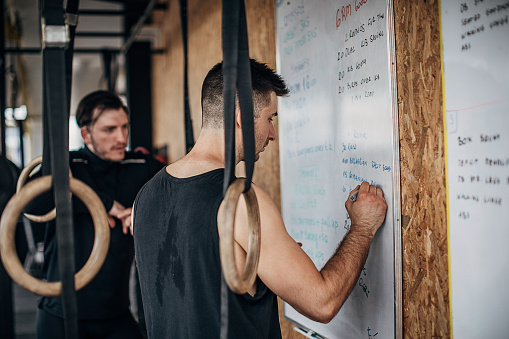 Personal trainer writing the workout instructions on the board in the gym.