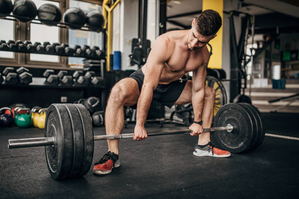 istock Young man exercising with weights in the gym 1253681996