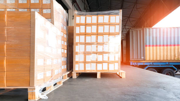 istock Large shipments pallet goods waiting for load into container truck at warehouse dock. Road freight cargo shipment by truck. Logistics and transportation 1253682120