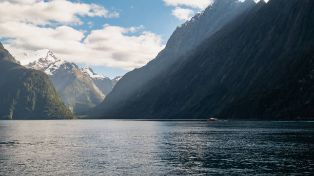 istock Boat sailing through fjord on a sunny day 1253684975